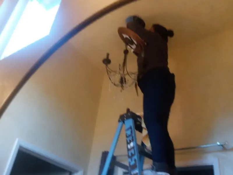 Electrician installing a chandelier in a Schiller Park residence